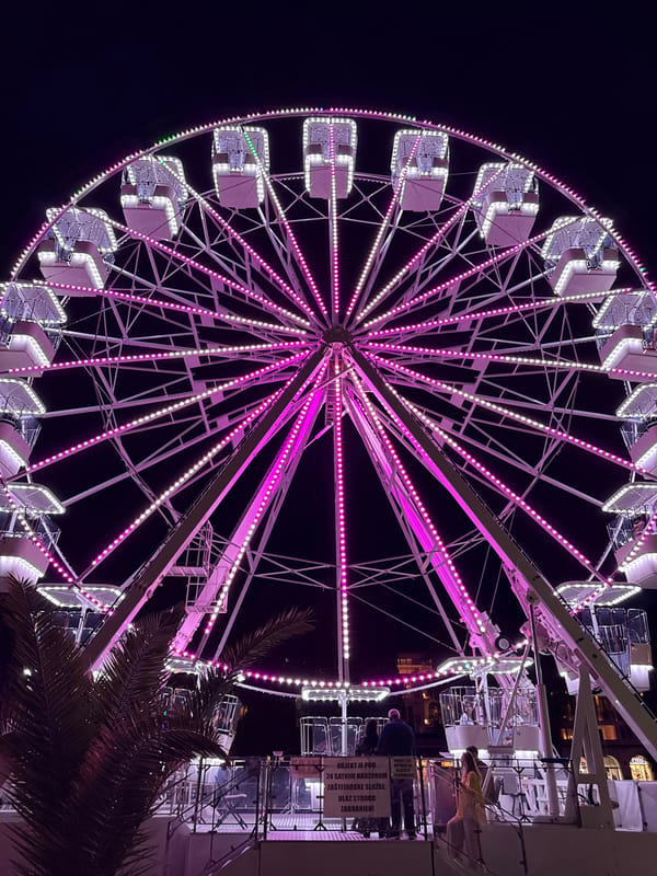 Evening scenes around Budva's illuminated waterfront Ferris wheel
