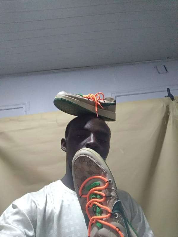 Man balances shoes, holds plants during indoor gathering