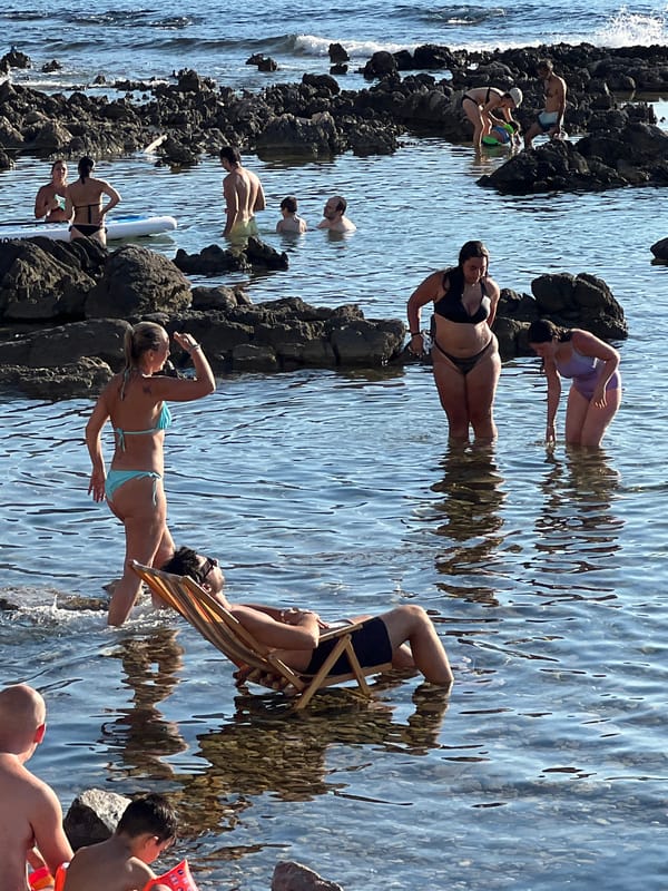 Deck chairs in the shallows at a Palermo rocky beach