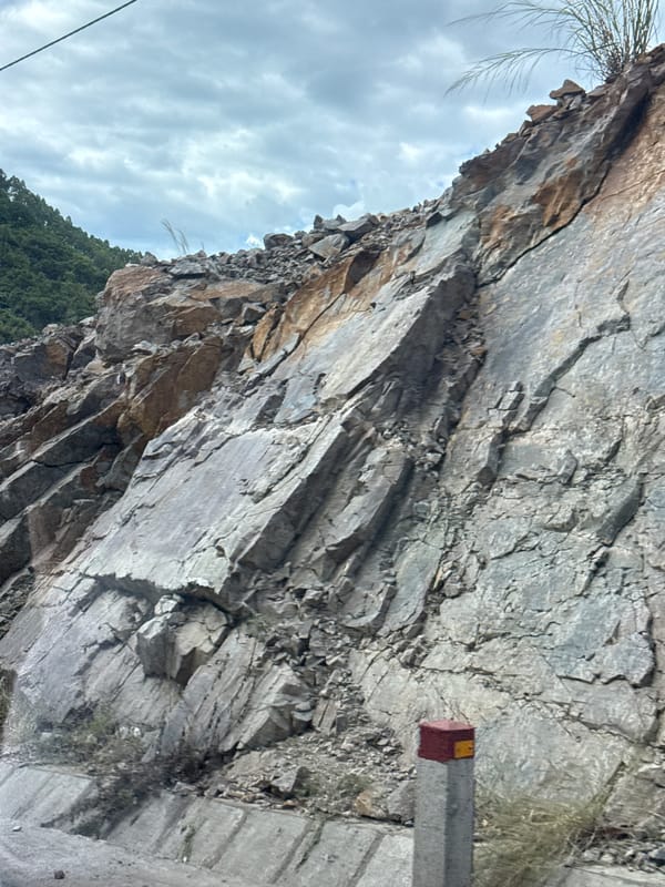 Fractured rock face with mineral staining lines a road in Binh Khe