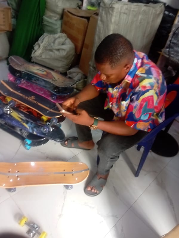 Man uses phone at skateboard shop in Fegge, Nigeria