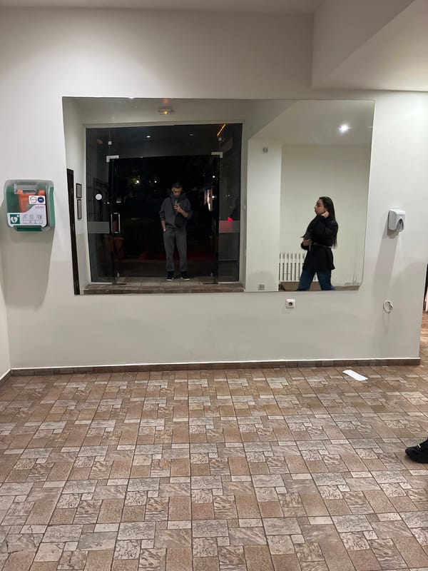 Mirror reflection captures two people in Karlovo building lobby