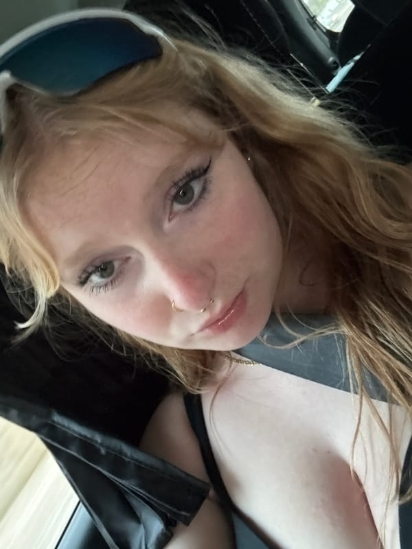 Blonde passenger with nose ring travels through suburban neighborhood