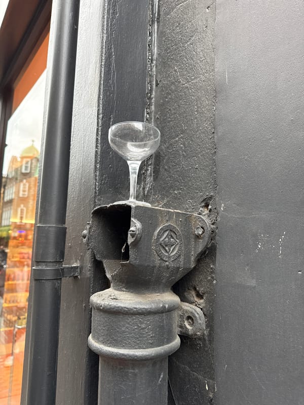 Wine glass balanced on aged pipe fixture in London