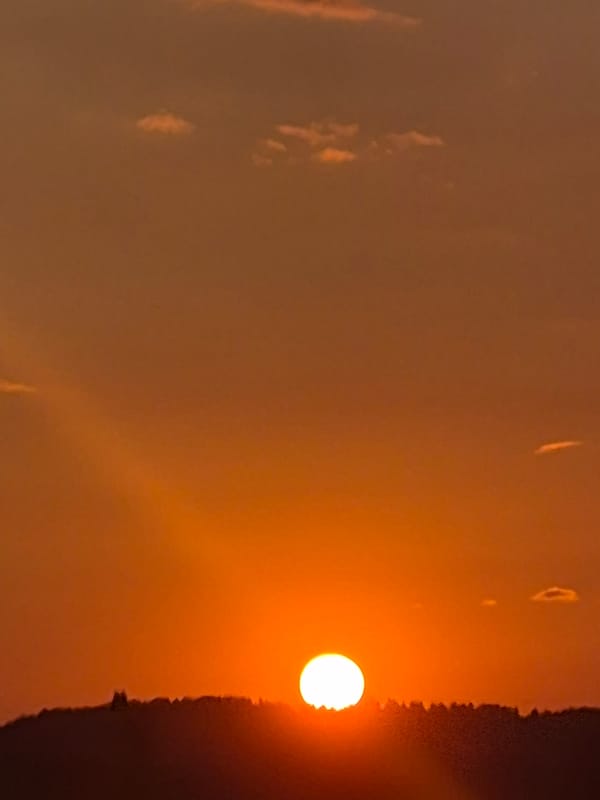 Sunset over silhouetted hills near Забегалово, rural Russia