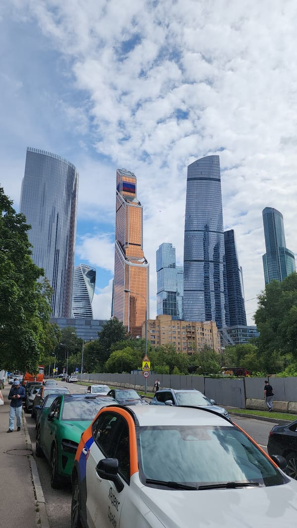 Green Xiaomi SU7 parked on Moscow street, skyscrapers behind