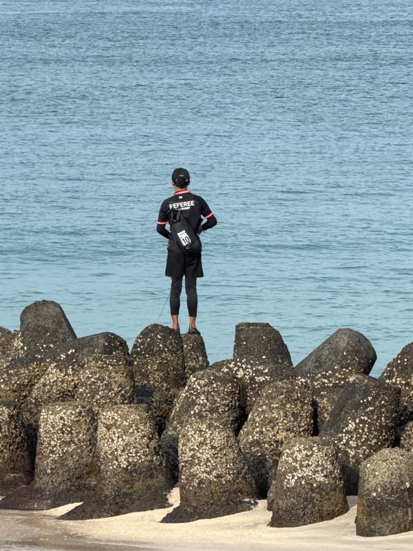 Man stands on breakwater facing ocean near Sanur Beach
