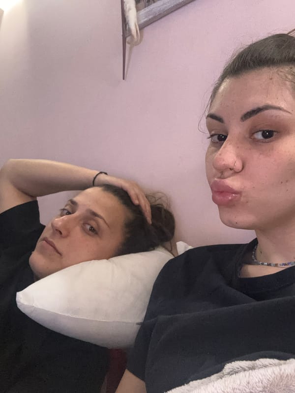 Two women rest indoors in Sofia, one flashing peace sign