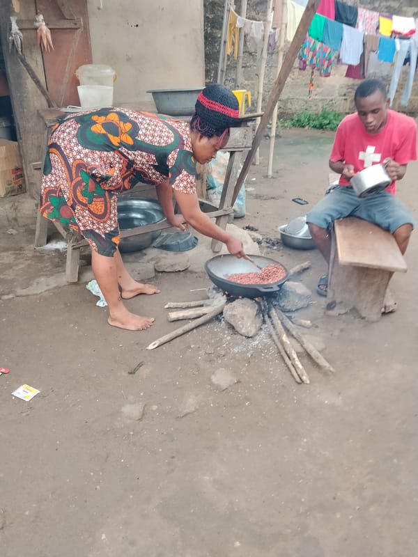 Woman cooks outdoors with large pan in urban setting