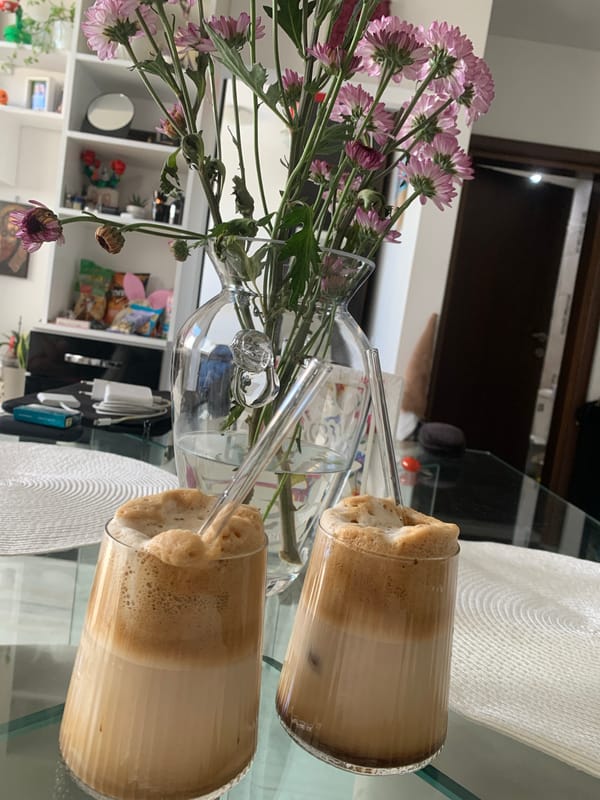 Morning still life: flowers and iced coffee on glass table