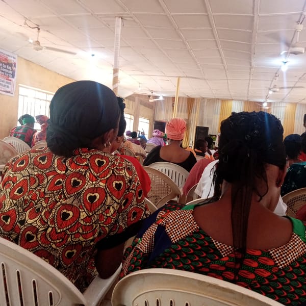 Women gather in white chairs for indoor event in Nsukka