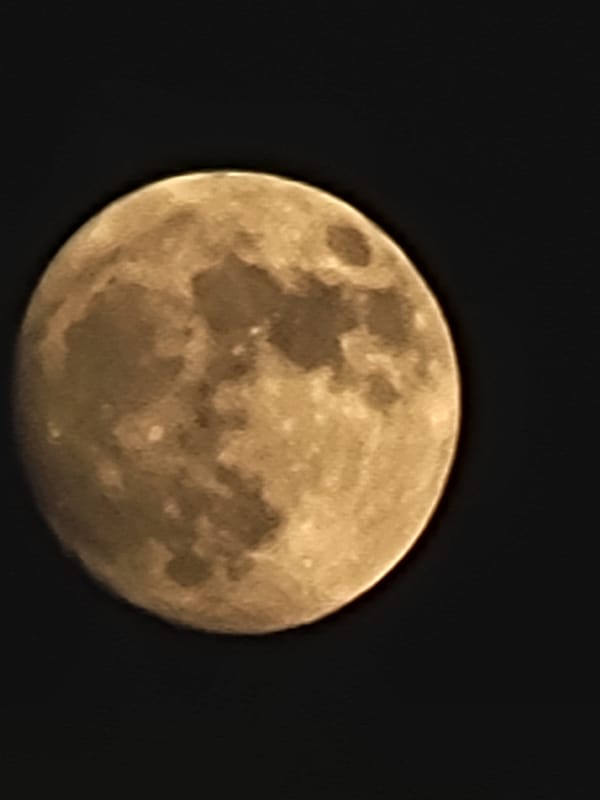 Full moon rises over Quarteira beach as ships pass offshore