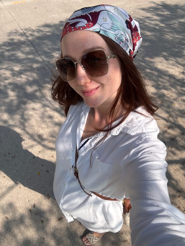 Woman in colorful headscarf smiles skyward in Choeng Thale
