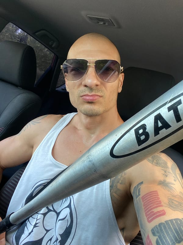 Tattooed person with baseball bat photographed in car, Pleven