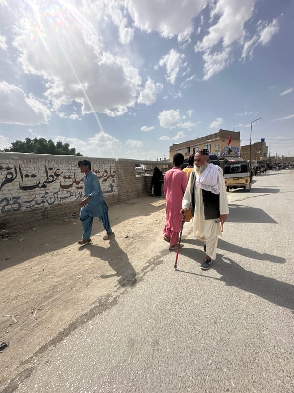 Elderly man walks with companions on Quetta road