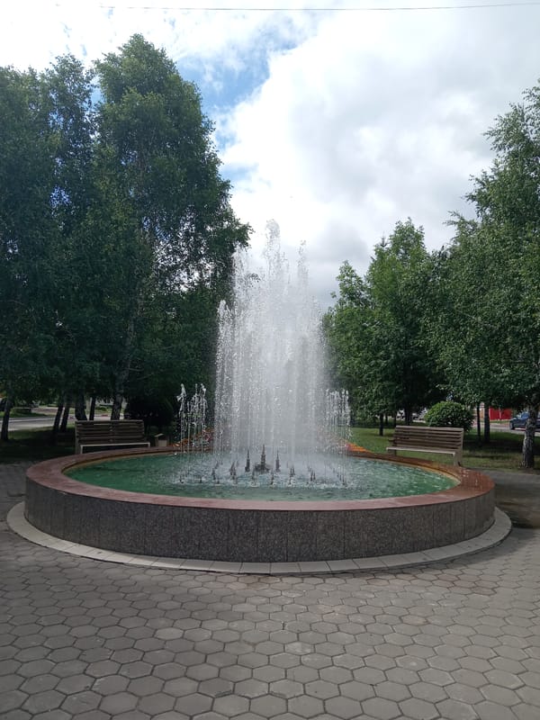 Morning in a Rudny park: fountains, flowers, and streets