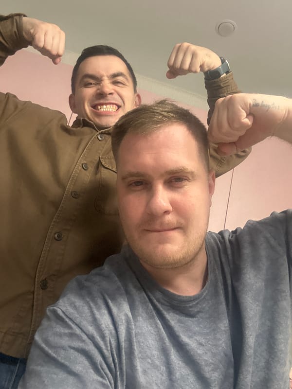 Two men pose for flexing selfie