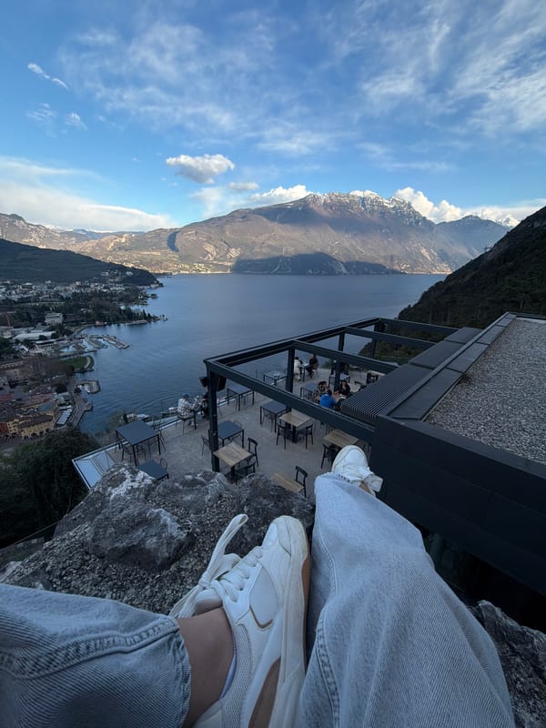 Person sits on rocks near modern building in Riva del Garda