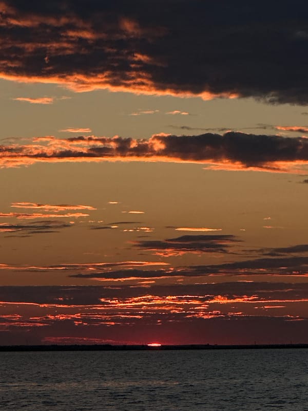 Sunset over a Kokshetau lake, sailboat on choppy water