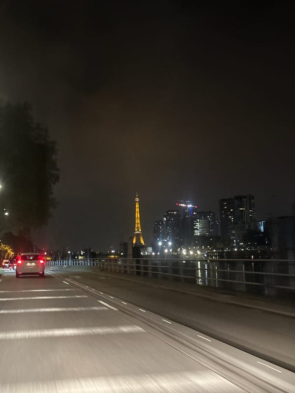 Nighttime traffic flows past illuminated Eiffel Tower in Paris