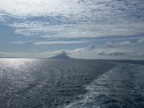 Ferry crossing open Norwegian waters past a lone coastal peak