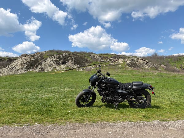 Black motorcycle parked in grassy field, Rusokastro Bulgaria