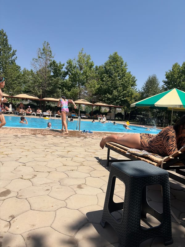 Sunny day at the pool, people swimming and lounging