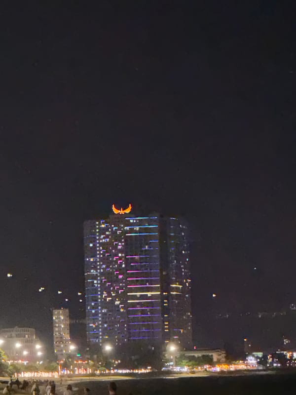 Nighttime coastal city scenes captured showing fountains, buildings, beach restaurant