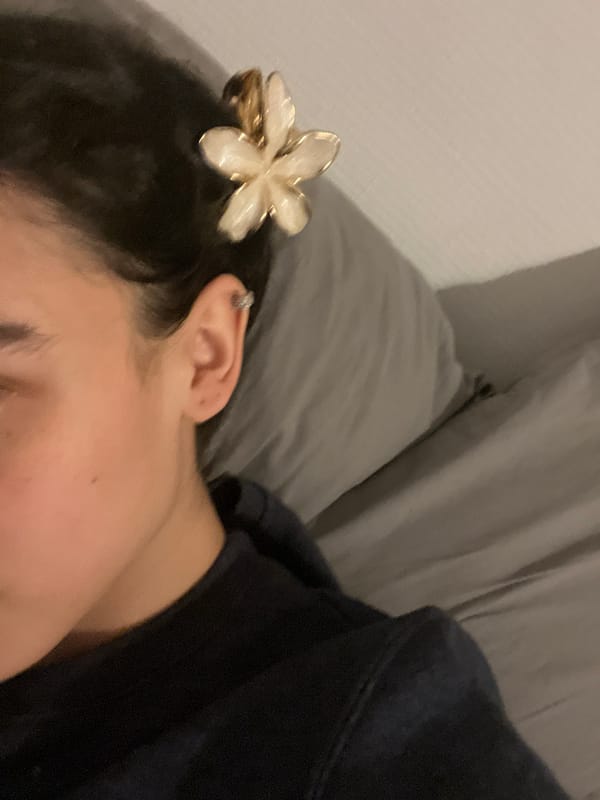 Person rests in bed with iPad, flower hair clip in Lyon