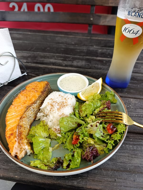 Grilled salmon, rice, and beer on a dark wooden table