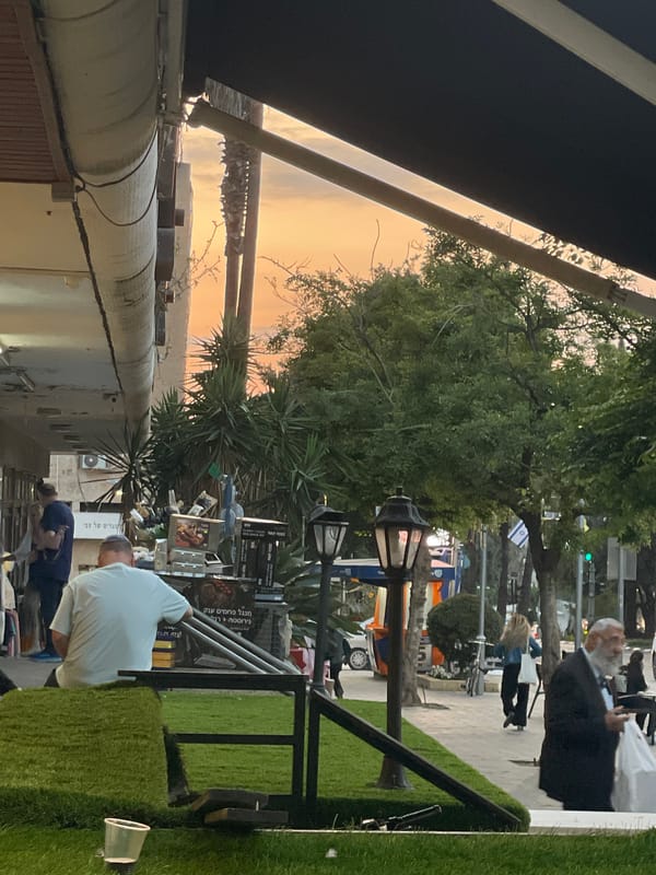 Evening gathering under awning captured in Raanana street scene