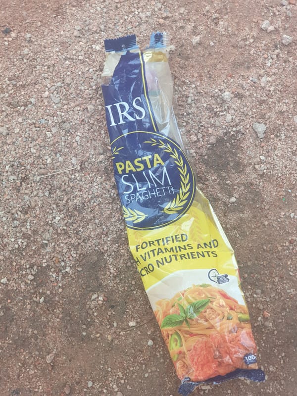 Discarded pasta snack bag spotted on rocky ground