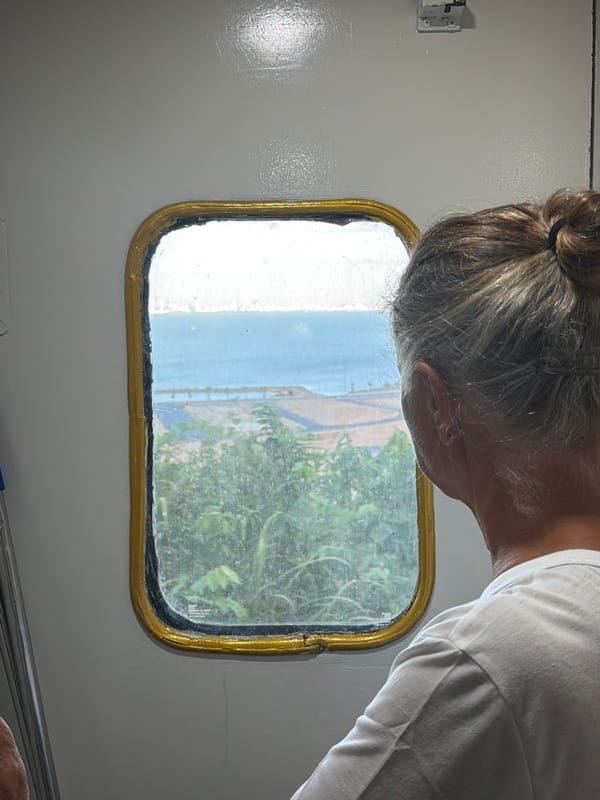 Person gazes at coastal landscape through window in Đà Nẵng