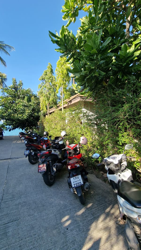 Beach scene with motorcycles and resort signage in Baan Mae Nam