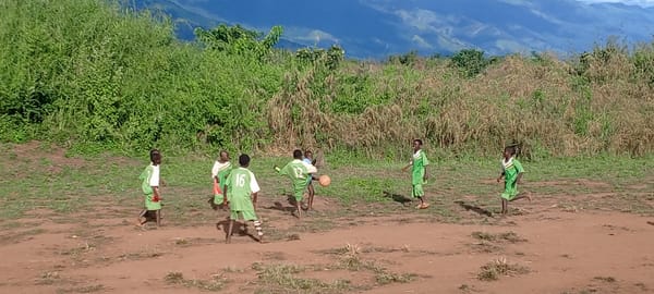 Children play informal soccer on dirt field in Ngalula, DRC