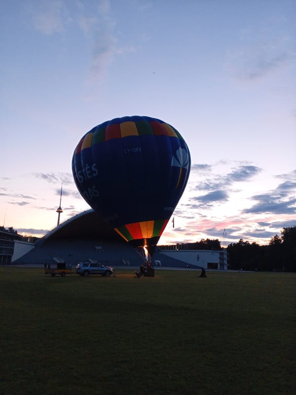 Blue hot air balloon inflates and preps for takeoff in open field