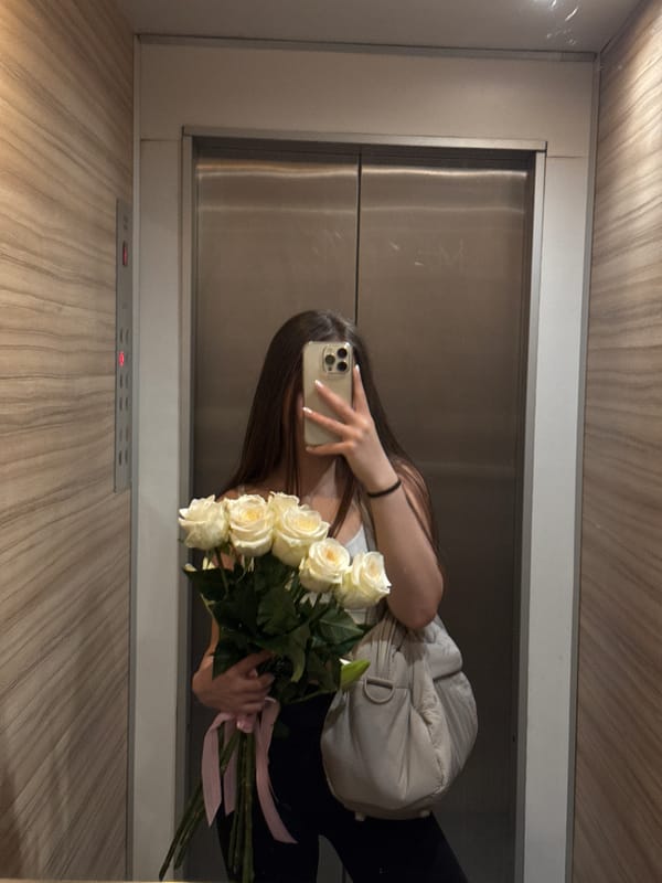 Woman takes elevator selfie with white rose bouquet in Sofia