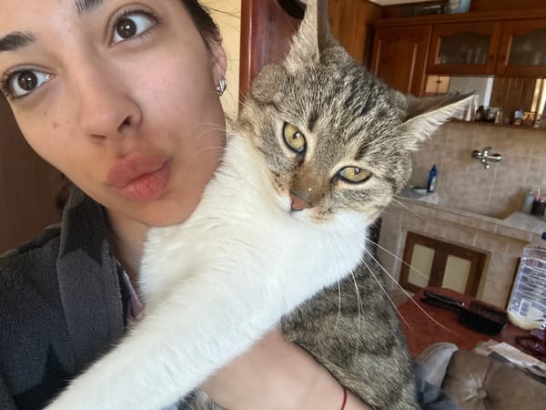 Woman poses with grey and white cat in Bulgarian home