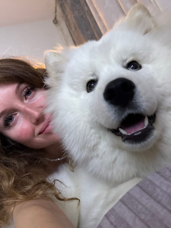 Woman photographed with white dog on bed in Chaikovsky