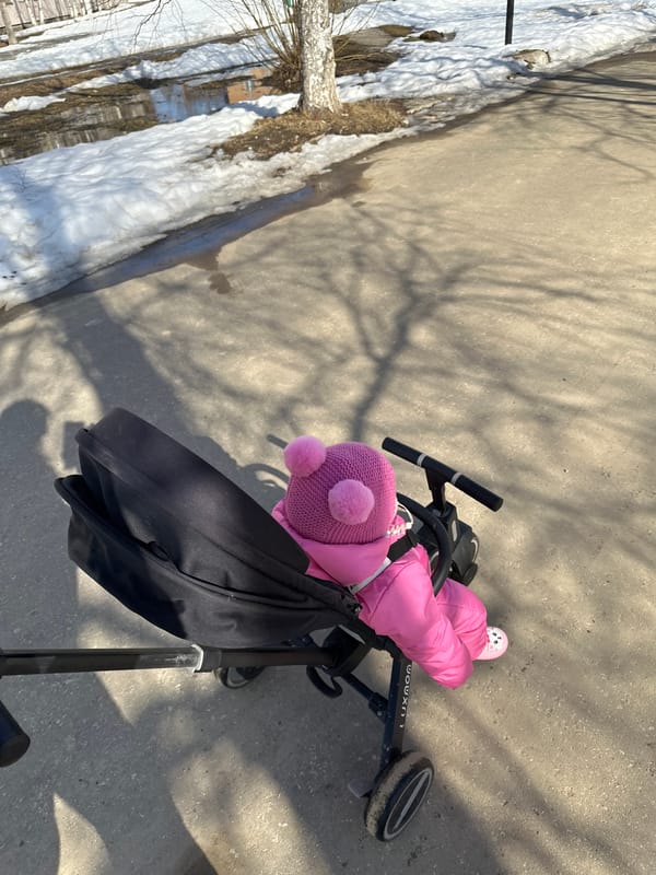 Child in pink snowsuit rides tricycle in Vuktyl