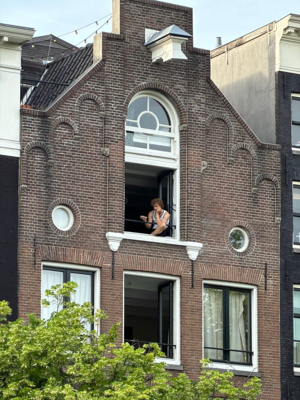 Woman leans from window of Amsterdam canal house