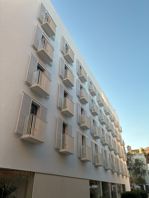Early morning traveler walks past modern building in Ibiza