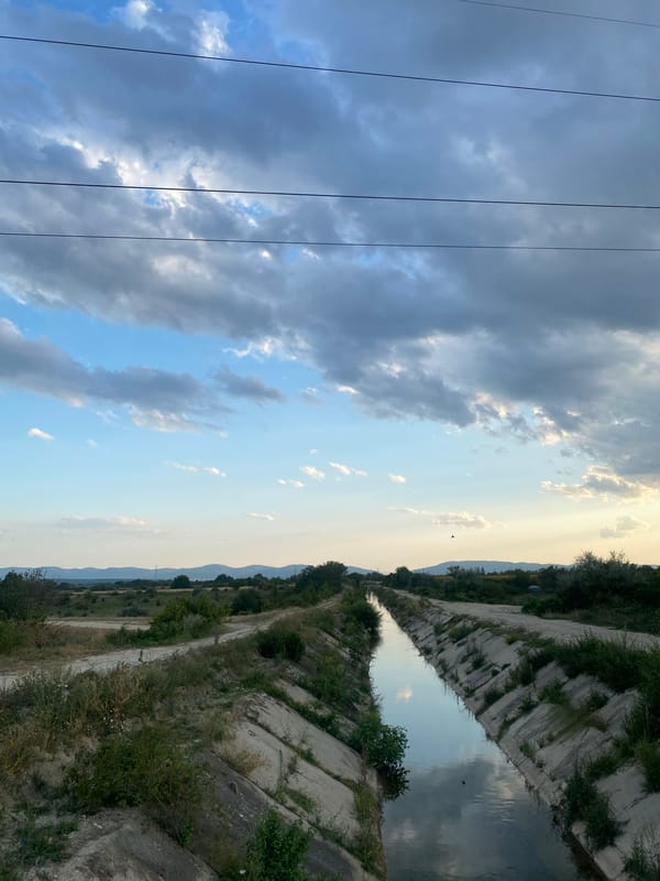 Calm irrigation canal through rural Shumen farmland at golden hour
