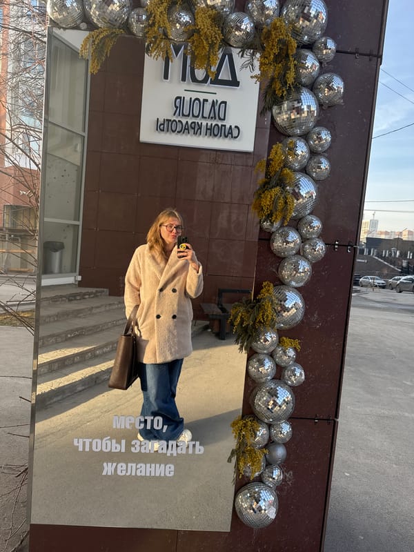 Woman takes selfie in mirrored building panel in Perm