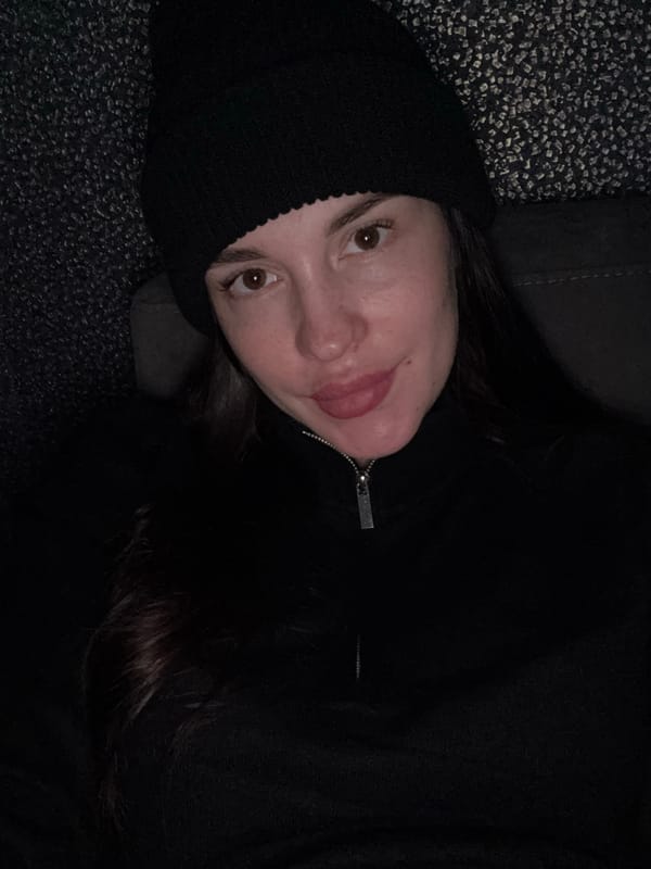Woman in black beanie photographed in low-light close-up