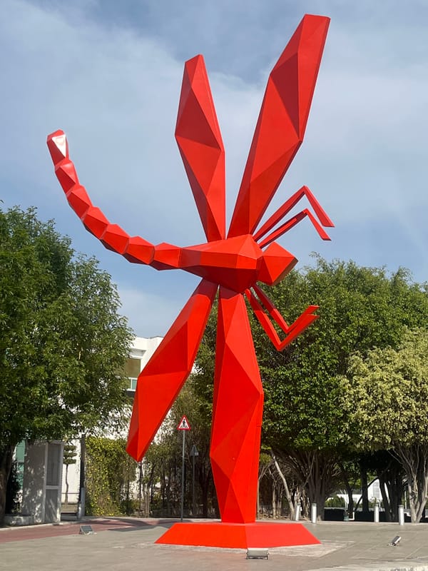 Red dragonfly sculpture and modern building documented by witness
