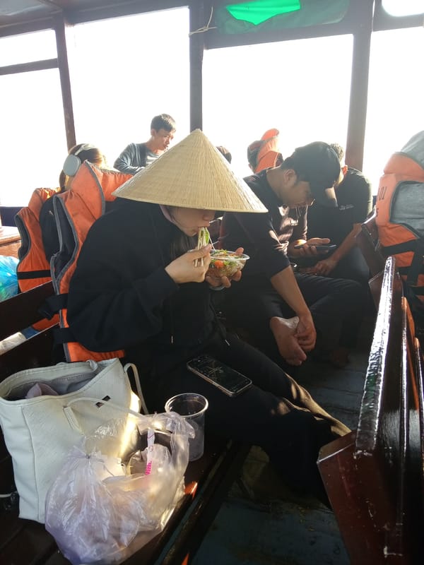 Person in conical hat eats aboard wooden boat Vietnam