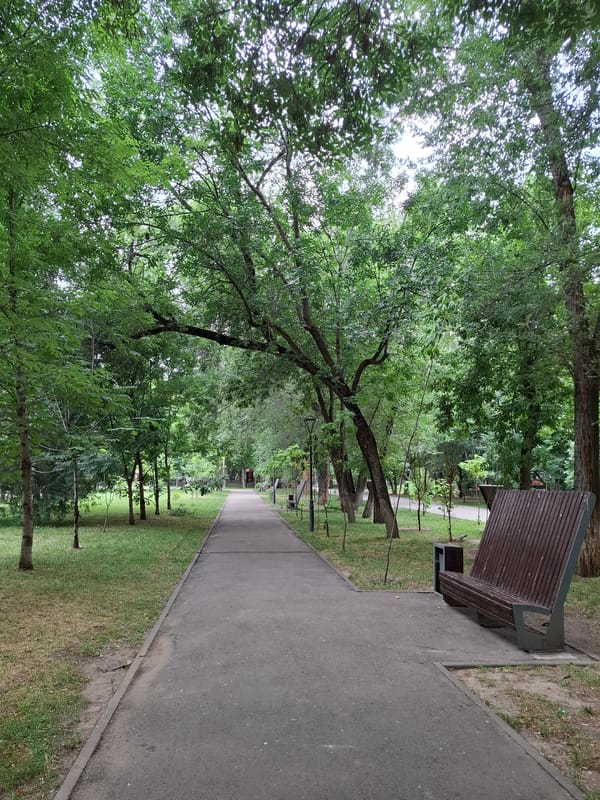 Inside a leafy Almaty park with chalk, benches, and a Soviet statue