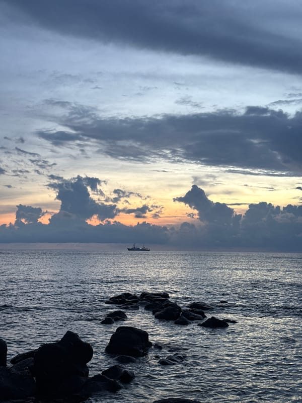 Dusk over Lý Sơn's rocky coastline, small boat in frame