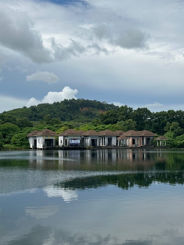 Abandoned stilted resort buildings line a quiet Thai waterfront